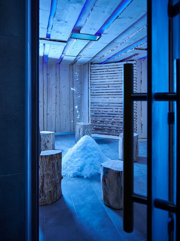Grotte de neige de Calicéo, avec éclairage bleu, neige au sol et assises en bois ; vue verticale depuis l'entrée.